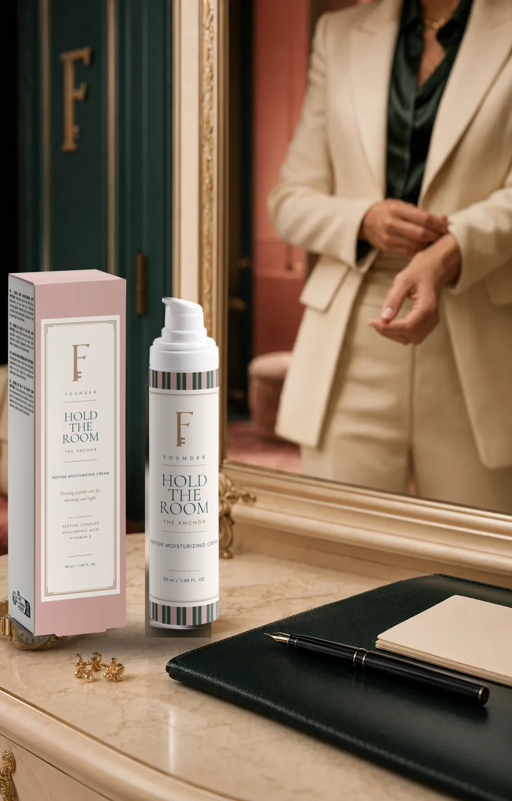 Hold the Room and its Desert Pink carton on a marble dressing table in front of a gilt mirror, a woman fastening her cuff in the reflection.